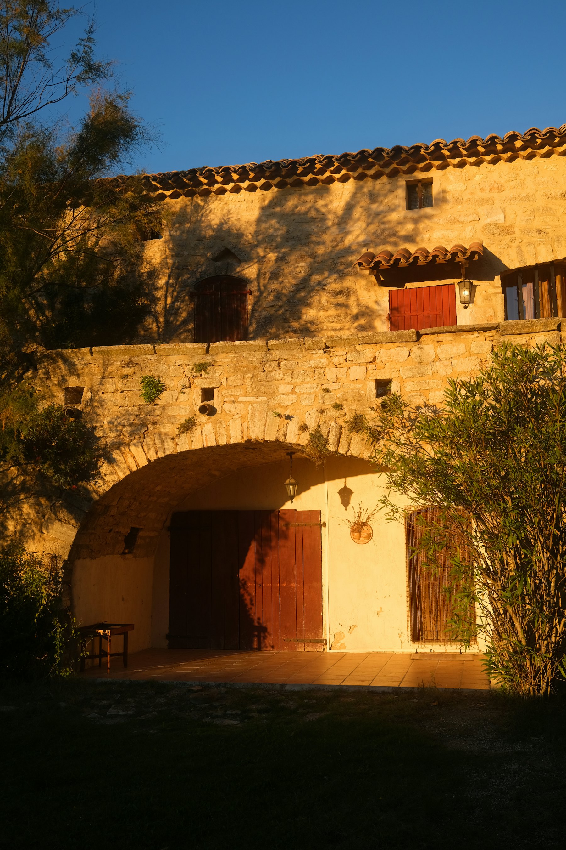 Façade en pierre d'une maison de village aux volets rouges